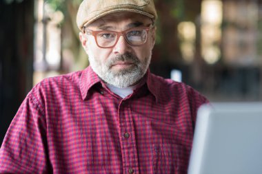 Halka açık bir yerde bilgisayar kullanan yetişkin Hipster adam