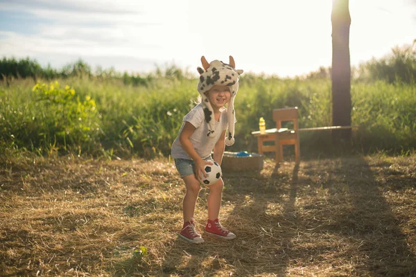 Niño en sombrero de animal divertido jugando con caballo de juguete de madera — Foto de Stock