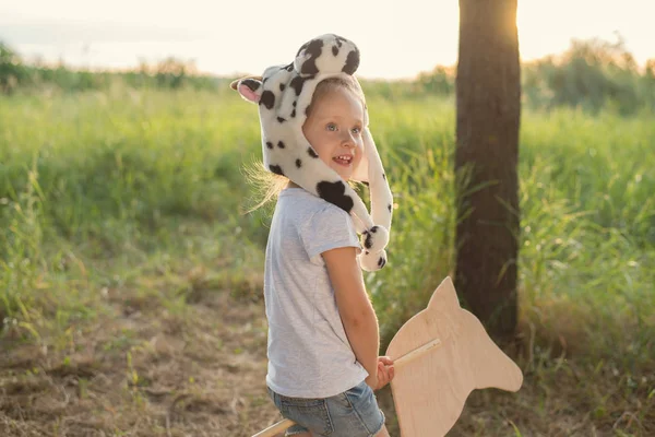 Niño en sombrero de animal divertido jugando con caballo de juguete de madera —  Fotos de Stock