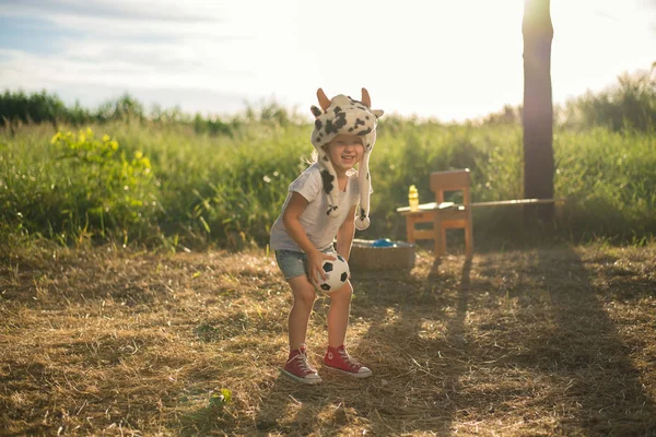 Дитина в смішному капелюсі тварин грає з дерев'яним іграшковим конем Ліцензійні Стокові Фото