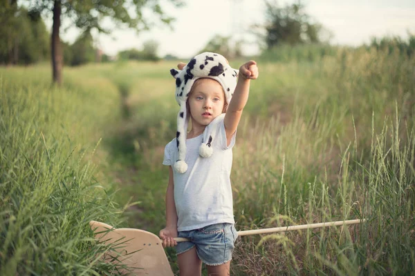 Kid in funny animal hat playing with wooden toy horse — Stock Photo, Image