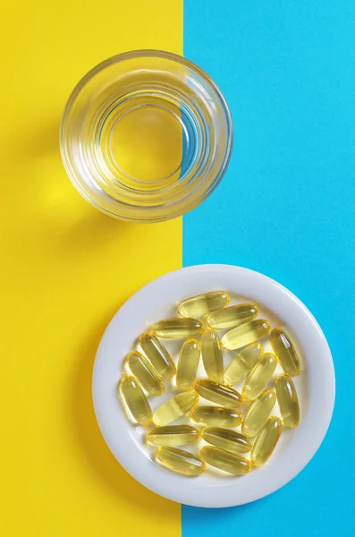 Vissen olie capsules en glas water — Stockfoto