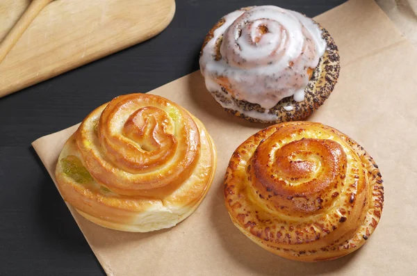 Verschillende Heerlijke Verse Gebakjes Bakpapier Zwarte Houten Tafel — Stockfoto