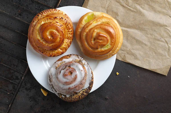 Various sweet buns on a plate on baking tray background, top view