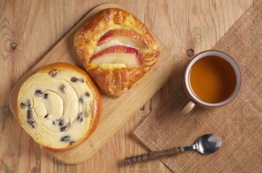 Kahvaltı için eski ahşap masada iki çörek ve bir fincan çay. 