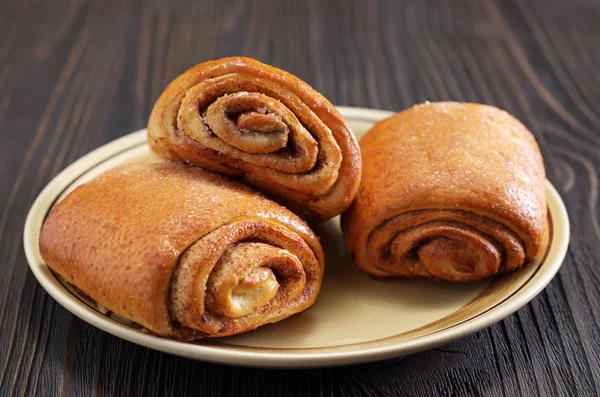 Simple cinnamon rolls on a plate on wooden background