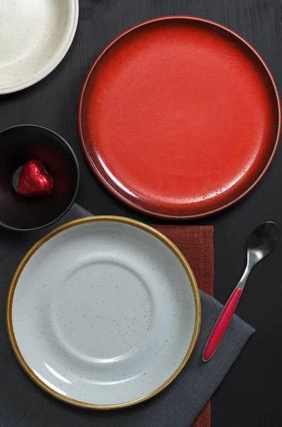 Colorful clean plates on a black wood table, top view