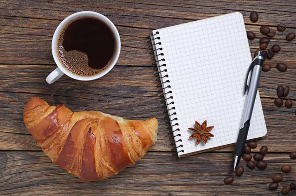 木制桌子上的咖啡 笔记本和羊角面包 — 图库照片
