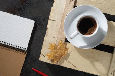 Bir fincan kahve, defter, kalem, sonbahar yaprağı. Üst görünüm