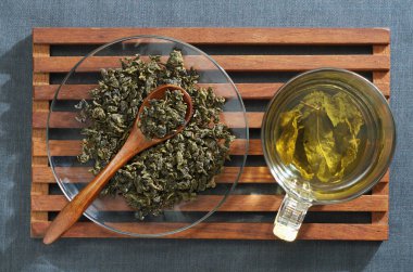 Kumaş zemin üzerinde kurumuş yapraklar olan bir fincan yeşil çay.