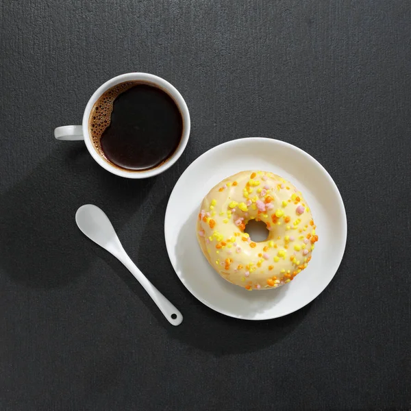 一杯咖啡和黑色石头背景的黄色甜甜圈 顶部视图 — 图库照片