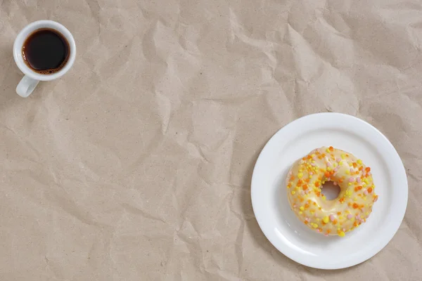 Пончик Глазурью Брызгами Чашкой Кофе Скомканном Бумажном Фоне Вид Сверху — стоковое фото