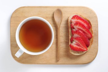 Çilekli tost ve beyaz arka planda kesme tahtasında bir fincan çay.