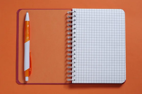 橙色背景特写笔记本和钢笔 顶部视图 — 图库照片