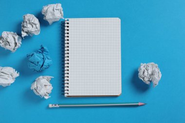 Mavi arkaplanda defter ve kağıt toplar, üst görünüm