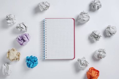 Beyaz arkaplanda defter ve kağıt toplar, üst görünüm