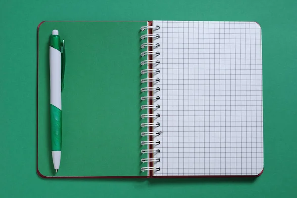 ノートブックとペンで緑の背景のクローズアップ トップビュー — ストック写真