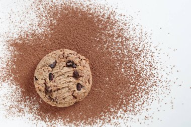 Kakao tozlu beyaz bir masada tek parça çikolatalı kurabiye.