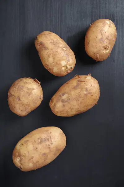 在黑色木制背景的新鲜有机土豆的正上方 — 图库照片