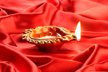 El yapımı Diwali kil lamba kırmızı saten zemin üzerine