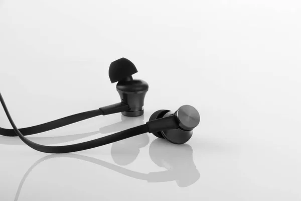 Stilvolle schwarze Kopfhörer auf weißem reflektierendem Hintergrund — Stockfoto