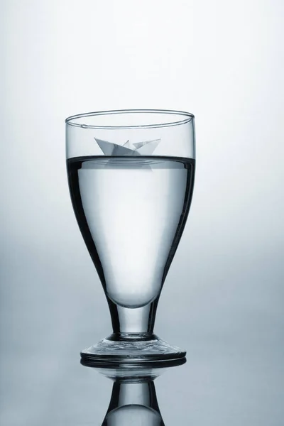 Weinglas mit Wasser und Origami-Papier-Boot-Konzept — Stockfoto