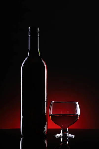 暗い背景にワインボトルとガラス — ストック写真
