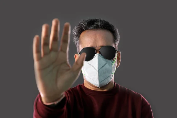 Indian Man wearing a N95 mask and sunglasses showing hands to stop virus, dust, pollution and smog