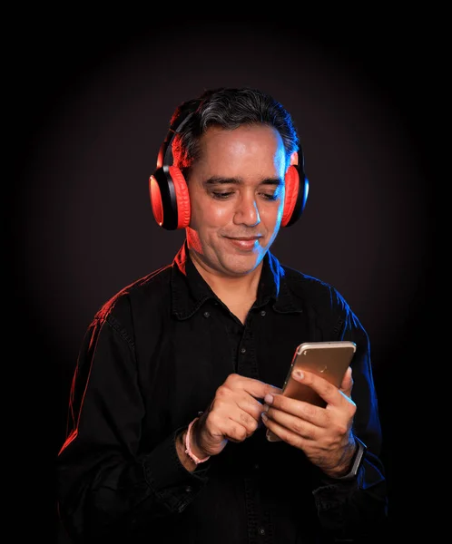 Indian Man listening to music on wireless headphones with a mobile in hand