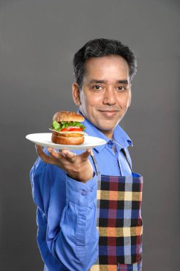 Gri Arkaplanda Bir Burger Olan Hintli Erkek Aşçı