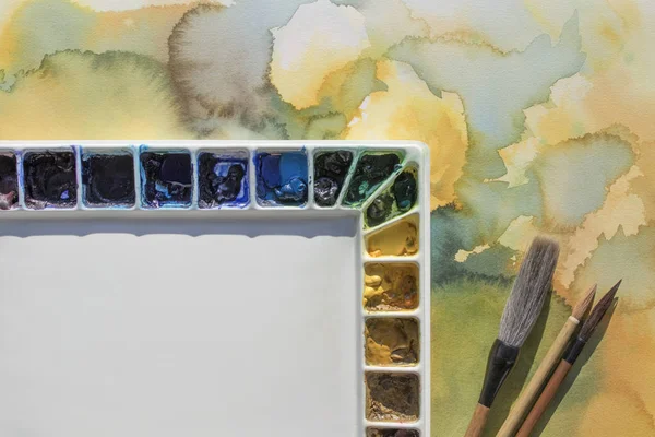 Palette with brushes on watercolor background — Stock Photo, Image