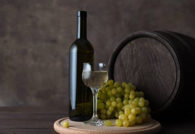 Bir şişe şarap, bir bardak şarap, üzüm ve varil 