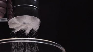 Metal elek ile siyah arka plan üzerine düşen rafine beyaz un yakın çekim
