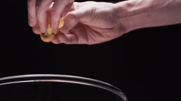 Рука трещит свежее яйцо в стеклянной чаше — стоковое видео