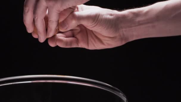 Рука трещит свежее яйцо в стеклянной чаше — стоковое видео