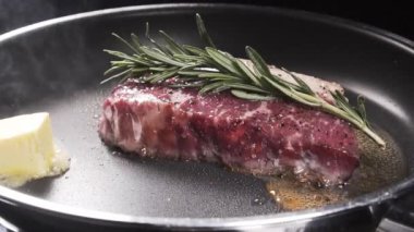 Dilimleri tereyağı için biftek bir tava düşüyor