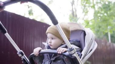 Anne, bir bebek arabası bebek alır. Bir çocuk kameraya görünüyor