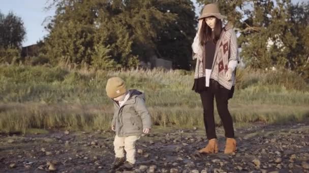 Maminka s malým chlapcem procházky na pláži — Stock video