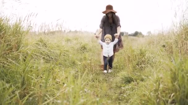 Moeder loopt met haar zoontje in het veld — Stockvideo