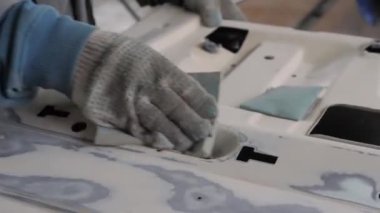 Bir araba servisinde, bir işçi bir parçaya macun koyar.