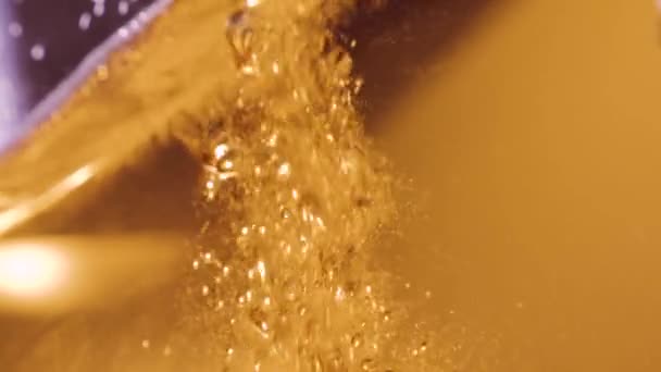 Le liquide orange est versé dans un verre. Beaucoup de bulles montantes 