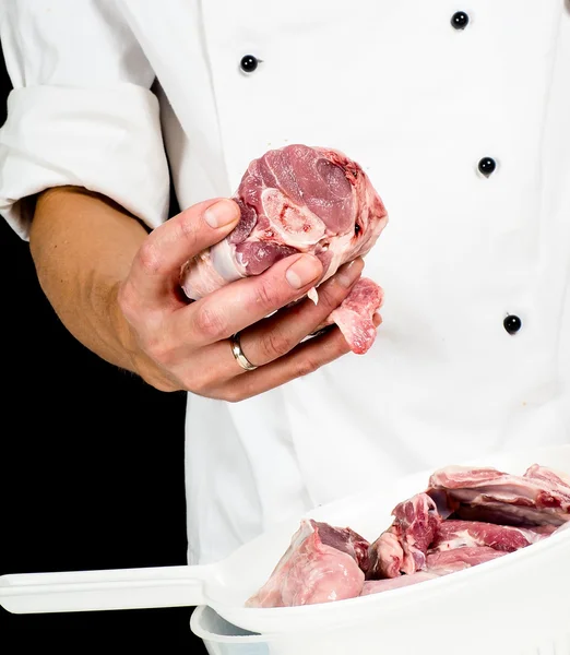 一个专业的厨师在夹克，拿着一块红色的肉 — 图库照片
