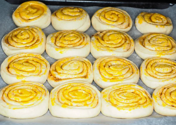 Primer plano de bollos de canela cruda después de la prueba con yema de huevo, en ba — Foto de Stock