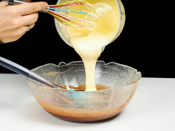 Femme versant Gogl-Mogl, dans un bol en verre avec chocolat — Photo