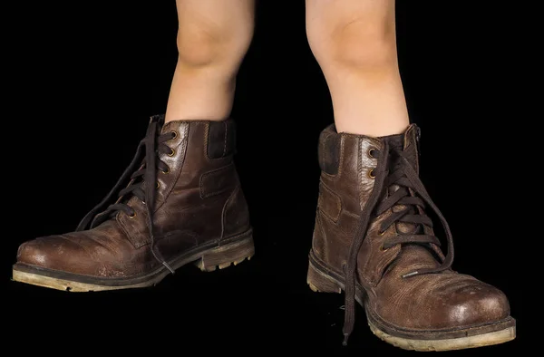 Niño usando un par de botas marrones desatadas y sin pulir demasiado grandes —  Fotos de Stock