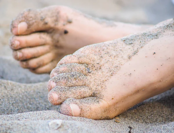 Fötter av en oigenkännlig kaukasiska person vilar i sand — Stockfoto