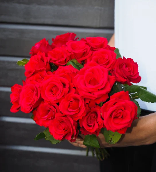 Male person holding a beautiful bouquet of red roses wearing whi Stock Photo