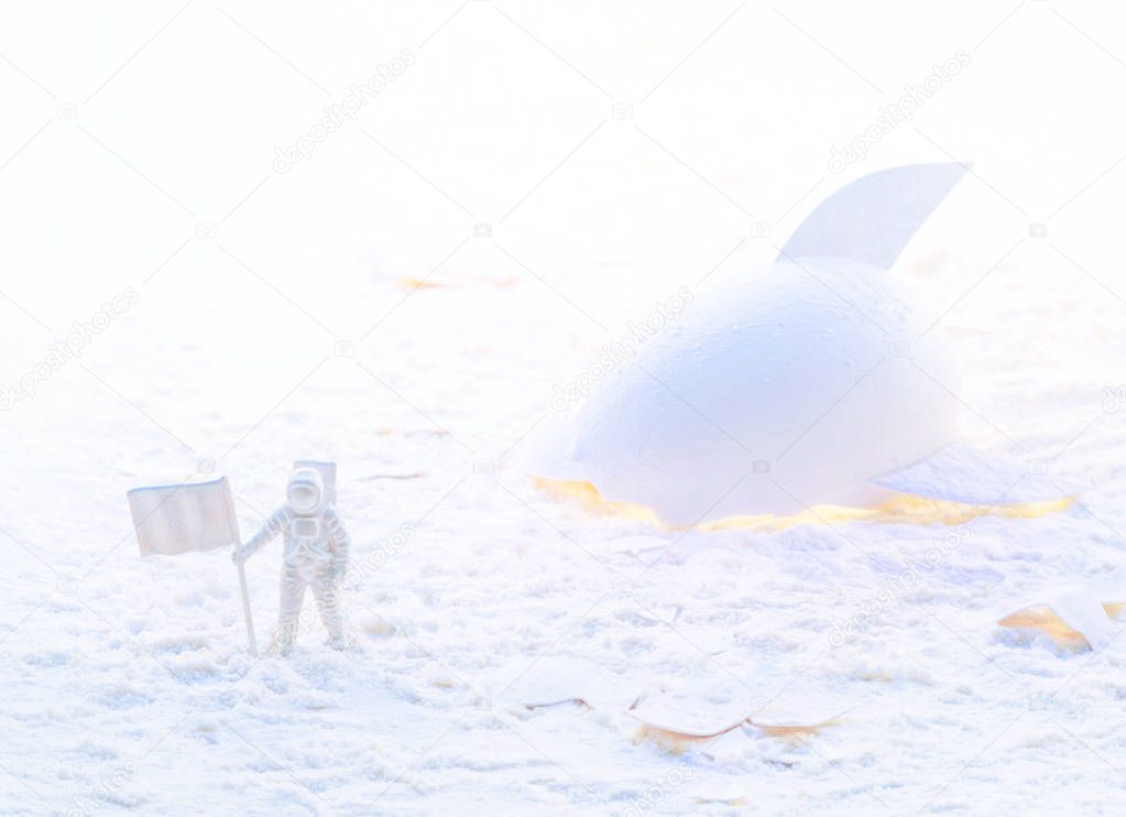 Conceptual high key photo of a white astronaut near the broken spaceship made of eggshell exploring snow planet. White space concept.