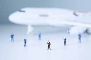 Oyuncak insanlar beyaz bir uçağa karşı duruyorlar.. 