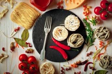 Makarna sebze ve eski bir arka plan üzerinde mutfak aksesuarları ile bir kompozisyon içinde